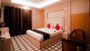 A hotel room with a bed, bedside table, chair, and a ceiling light fixture.