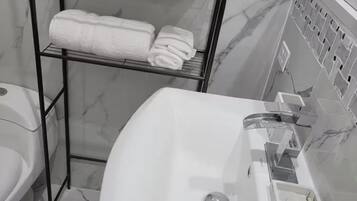 Chuveiro, toalhas de banho, sabonete, papel higiênico