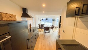 A modern kitchen with a central island, wooden flooring, and a dining area with a table and chairs.