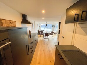 Eine moderne Küche mit einer zentralen Kochinsel, Holzböden und einem Essbereich mit Tisch und Stühlen.