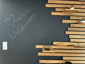 Eine Wand mit einer Tafel, auf der der Schriftzug „Willkommen“ und ein Willkommensschild stehen.