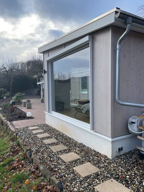 Ein modernes Gebäude mit großen Fenstern, einer Betonfassade und einem Kiesweg, der zu einer Tür führt.