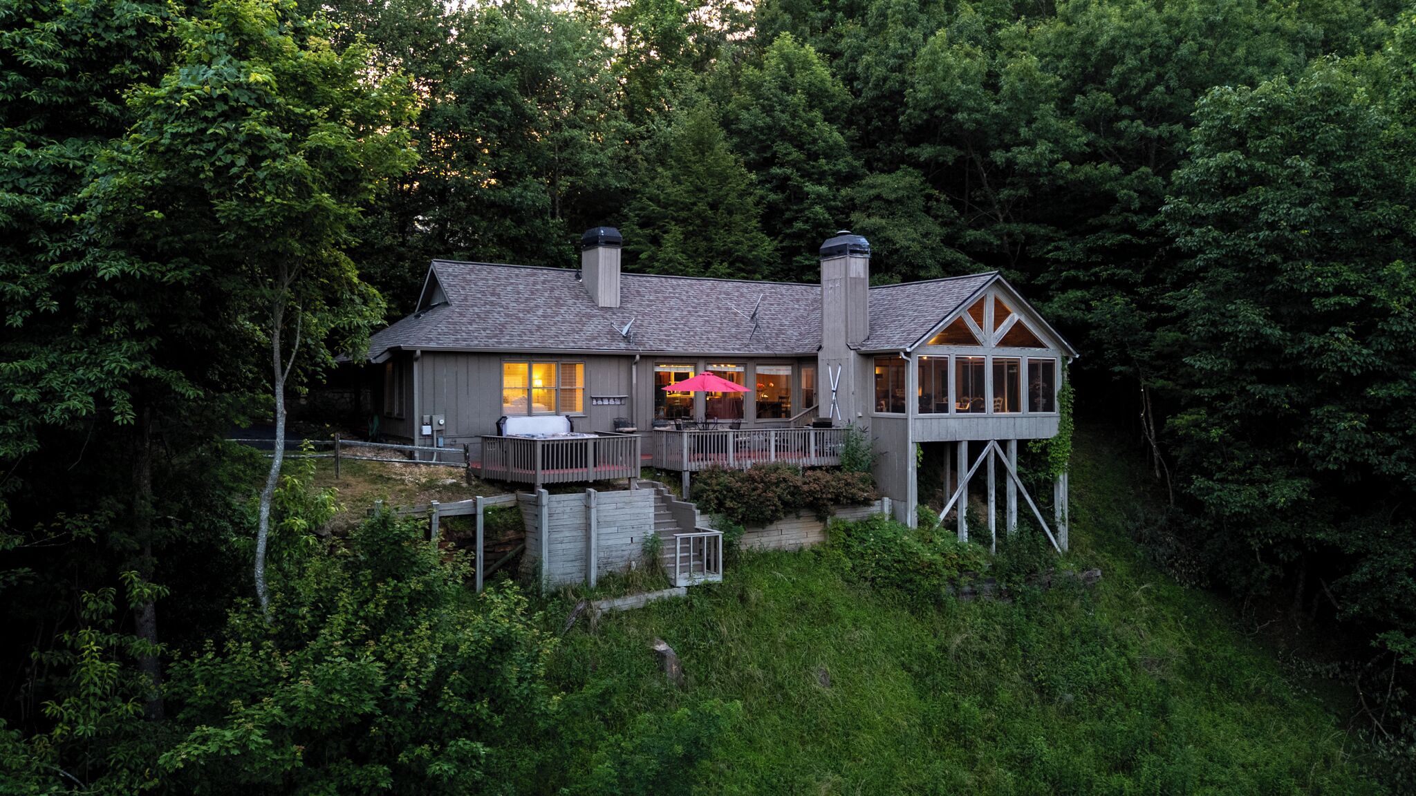A house with a deck, a hot tub, and a covered outdoor seating area.