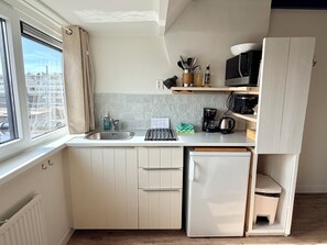Een kleine keuken met een spoelbak, een koffiezetapparaat en een magnetron.
