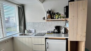 A compact kitchen with a sink, a coffee maker, and a refrigerator. - Nice studio with small terrace and parking lot. Only 200 meters from the sandy beach (Bergen aan Zee)