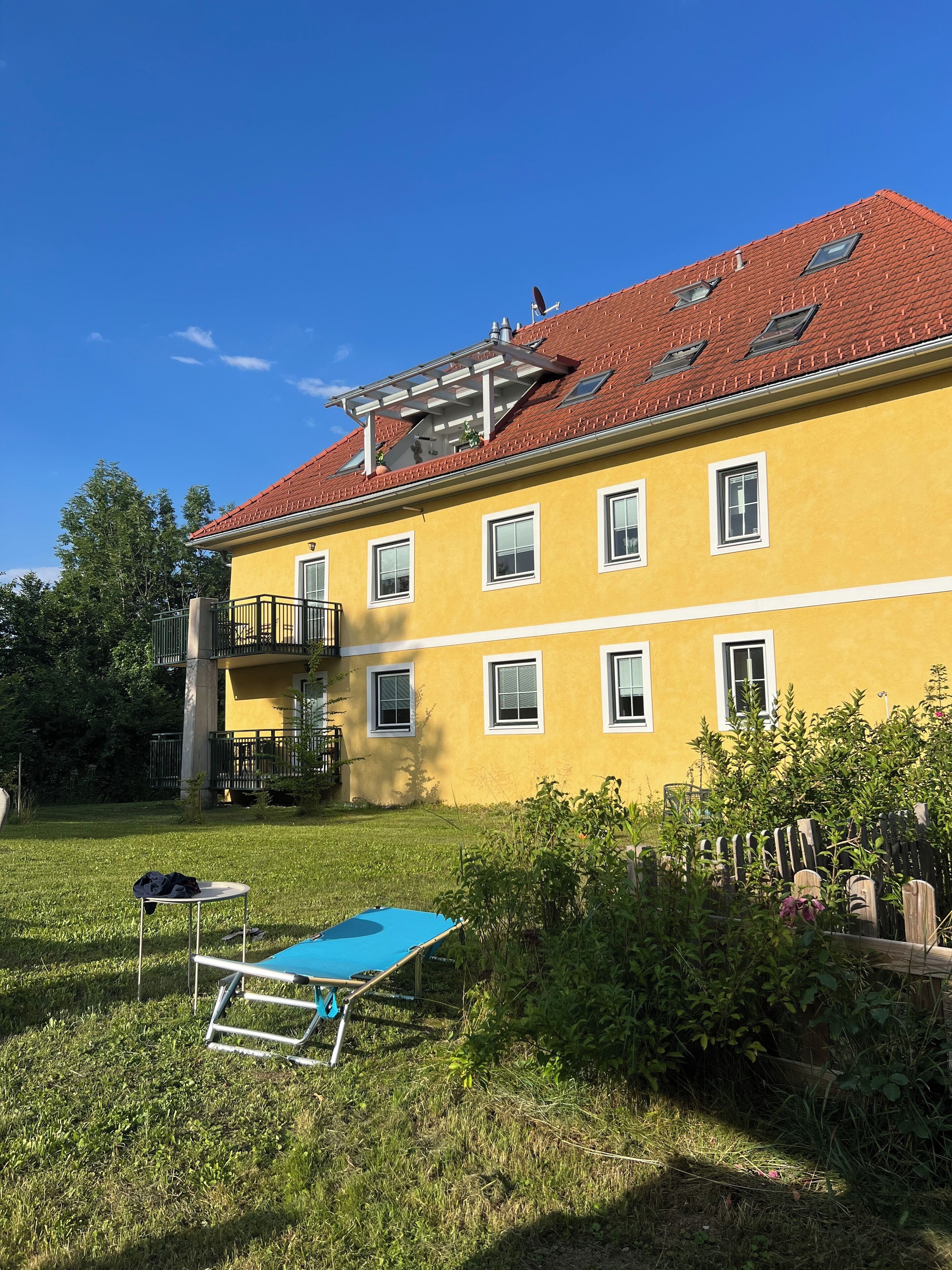 Un bâtiment jaune avec un toit rouge, de nombreuses fenêtres et un balcon.