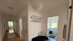 A hallway with wooden flooring, a black table, and a hanging metal rack.
