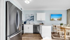 A modern kitchen with stainless steel appliances, white cabinetry, and a wooden dining area. - ☀️Beach Access-3 Pools-Gulf View-Gulf Place Cabanas 210 (Santa Rosa Beach)