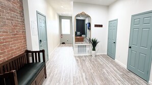 A hallway with light-colored wooden flooring, a brick wall on the left, and three light blue doors. - Stylish Historic Loft in Downtown Dubuque. Walk to Dining & Riverwalk (Dubuque)