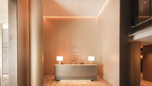 Bancada de recepção com duas luminárias, um logotipo e design de interiores moderno.