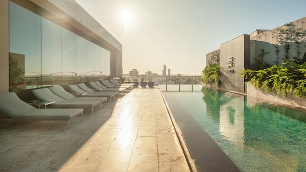 Uma área de piscina no terraço com espreguiçadeiras e vista desobstruída para o horizonte da cidade.