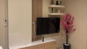Un saló modern amb televisió integrada, un armari de fusta i una planta en test.