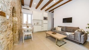 Un espacio de estar moderno con pared de piedra, comedor, sofá y cocina.