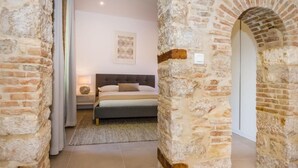 Un dormitorio con pared de piedra, una cama, una mesita de noche y un cuadro enmarcado en la pared.
