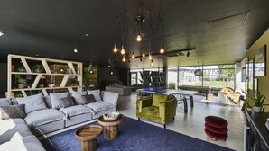 A modern living room with a sectional sofa, a green armchair, a ping pong table, and a blue carpet. - For Students Only Nottingham Two (Nottingham)