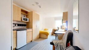 A compact, modern apartment with a kitchenette, a bed, a desk, and a chair. - For Students Only Nottingham Two (Nottingham)