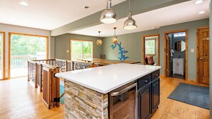 A spacious kitchen with a large island, wooden flooring, and pendant lighting. - Deep Creek Escape: w/ Theater, Fire Pit & Dock (Swanton)
