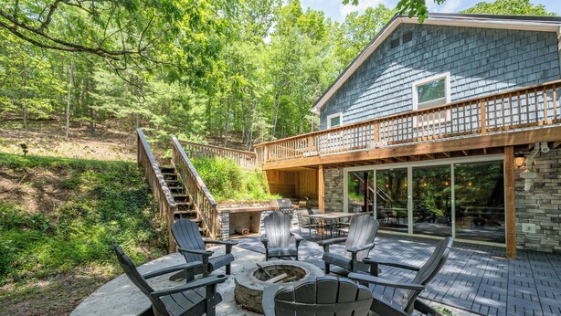A deck with Adirondack chairs, a fire pit, and a stone fireplace. - Deep Creek Escape: w/ Theater, Fire Pit & Dock (Swanton)