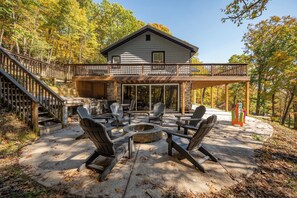 A two-story house with a deck, outdoor seating area, and a fire pit.