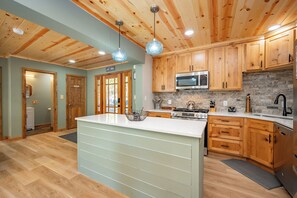 A kitchen with wooden cabinets, a central island, a microwave, and a stove.