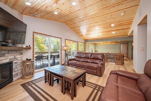 A spacious living area with a fireplace, leather sofa, and a dining table.