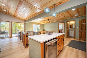 A spacious kitchen with wooden cabinetry, a large island, and pendant lighting.