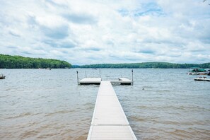 A wooden dock extending into a lake with a forested shoreline in the background.