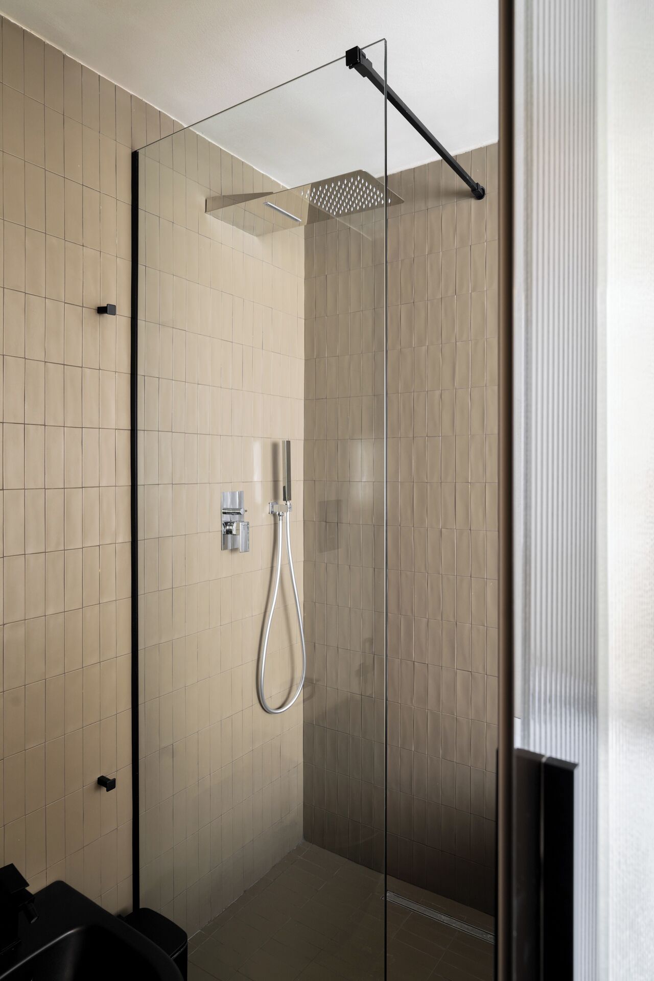 A modern shower with a glass enclosure, a handheld showerhead, and a wall-mounted control panel.