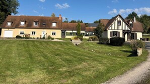 Une grande maison à deux étages, dotée d’une pelouse bien entretenue et d’une allée gravillonnée.