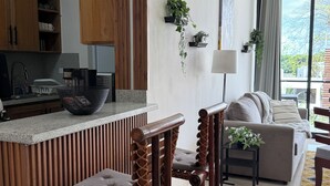 Eine moderne Küche mit Holzschränken, einer integrierten Kochinsel und einer Sitzecke mit einer Couch und zwei Holzstühlen.
