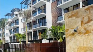 Ein modernes Apartmenthaus mit Pool, Balkonen und einem Holzzaun.