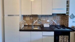 A modern kitchen with white cabinets, a black countertop, and a unique rope chandelier. - R home double room with private bathroom (Ischia)