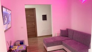 A living room with a purple sofa, a small table with a board game, and a pink wall. - R home double room with private bathroom (Ischia)