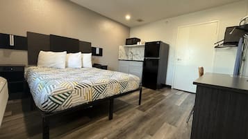 Une chambre d’hôtel compacte comprenant un lit, des tables de chevet, une kitchenette et un petit coin salon.