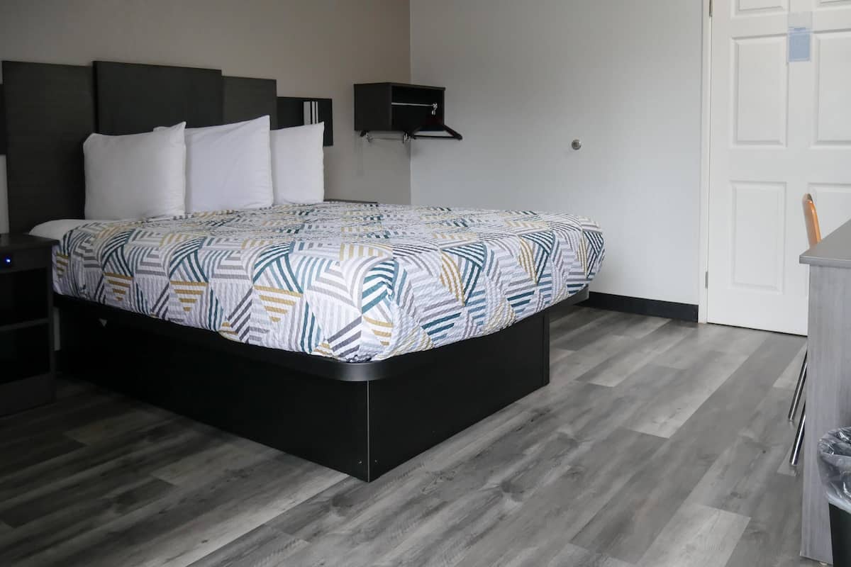 A modern bedroom with a bed, a bedside table, a wardrobe, and a door.