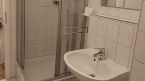 Ein Badezimmer mit einer gläsernen Duschkabine, einem weißen Waschbecken und einem Spiegel darüber.