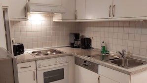 Eine Küche mit weißen Schränken, einem Herd, einer Kaffeemaschine und einem Geschirrspüler.