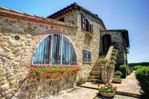 Traditional stone building with a rustic charm, featuring a tiled roof and flower-adorned facade.