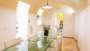 Eine moderne Küche mit einem Glastisch, weißen Stühlen und einem Blumentopf.