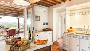 A kitchen with a marble countertop, wooden cabinets, and a view of the outdoors. - Casale Ombrone 11, Emma Villas (Campagnatico)