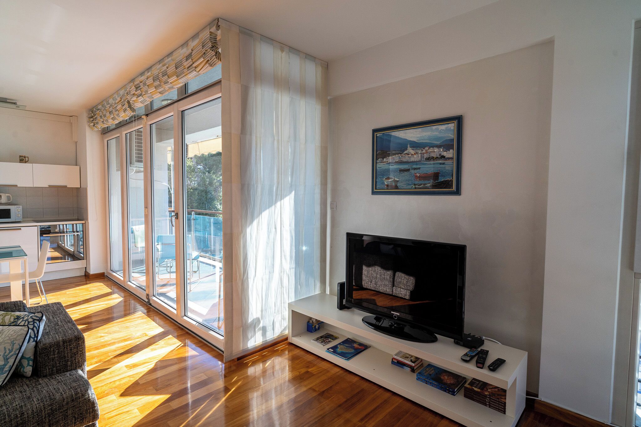 Una sala de estar moderna con un televisor de pantalla plana, un sofá y un comedor con mesa y sillas.