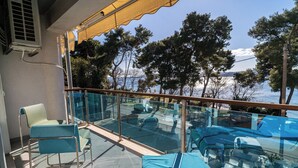 Un balcon doté de balustrades en verre, d’une chaise et d’une table recouverte d’une housse bleue.