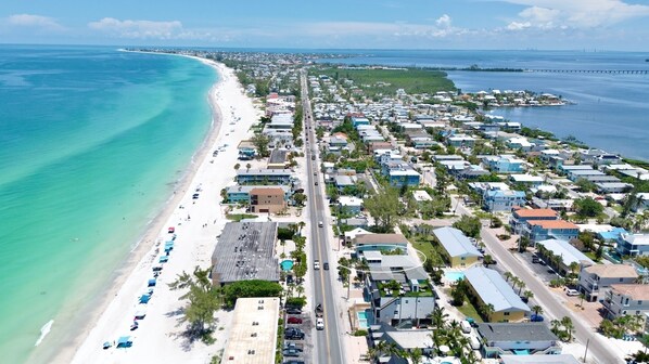 A coastal town with a beach, houses, and a road.