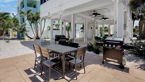 Un patio al aire libre con mesa y sillas, una parrilla y una zona de estar cubierta.
