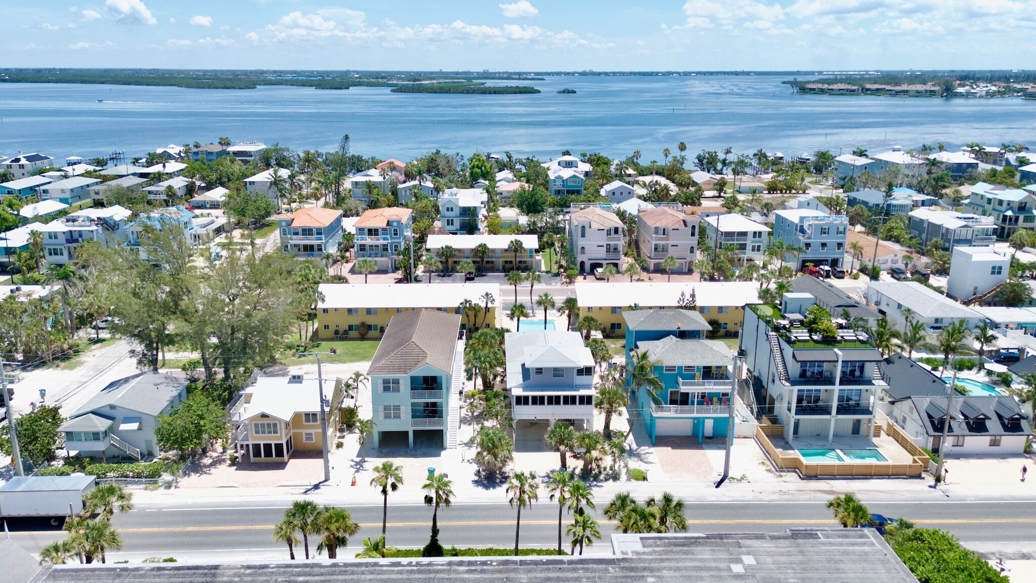 A coastal residential area with houses, palm trees, and a view of the ocean.
