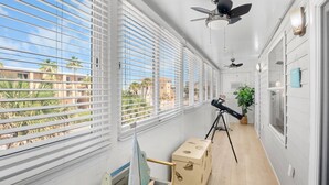Un balcon avec des stores blancs, un télescope et un trépied pour télescope.