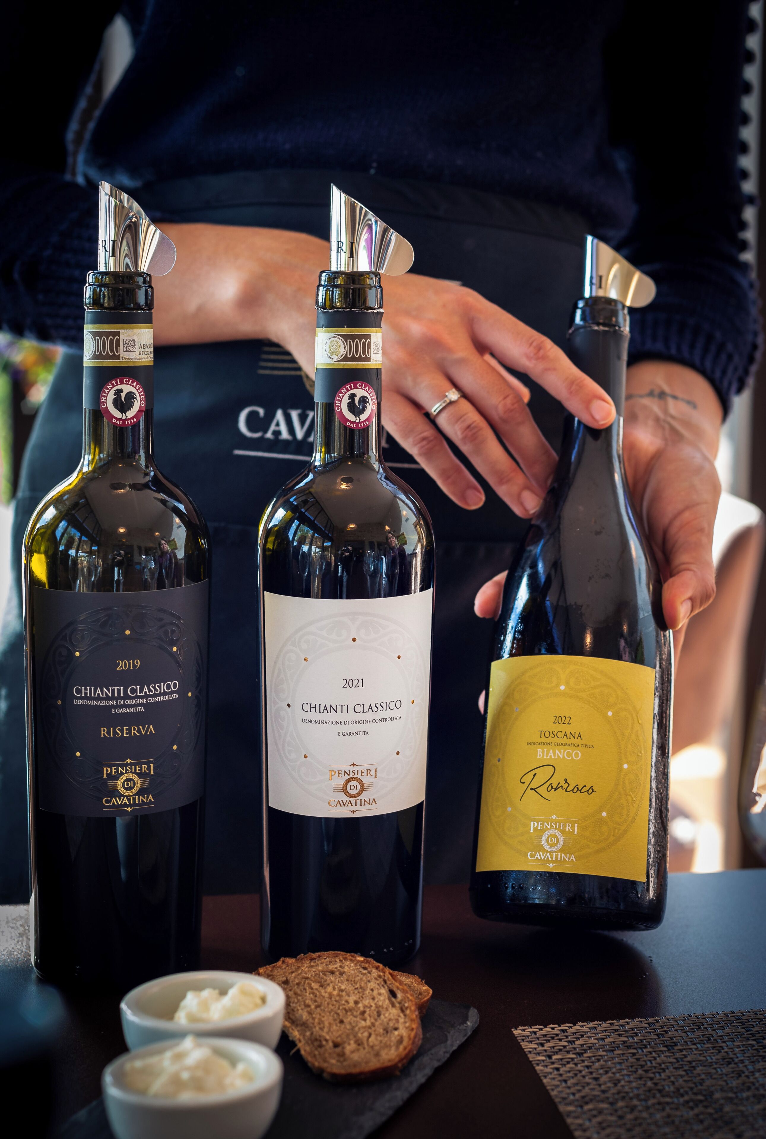 Three bottles of Chianti Classico wine from 2019, 2021, and 2022, with a person holding the 2022 bottle.