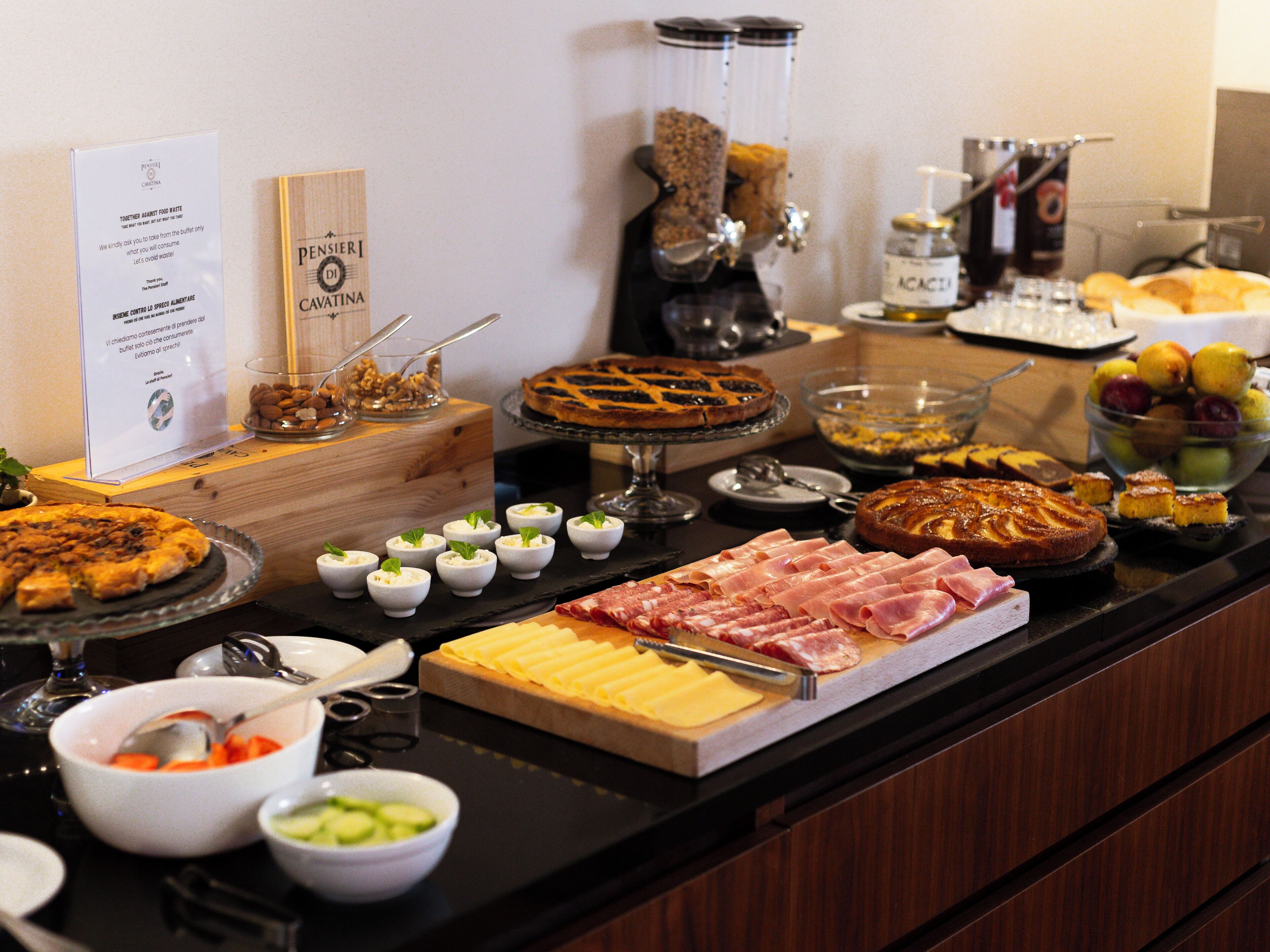 Een buffet met diverse etenswaren, waaronder pizza, een kaasplankje en vleessoorten.