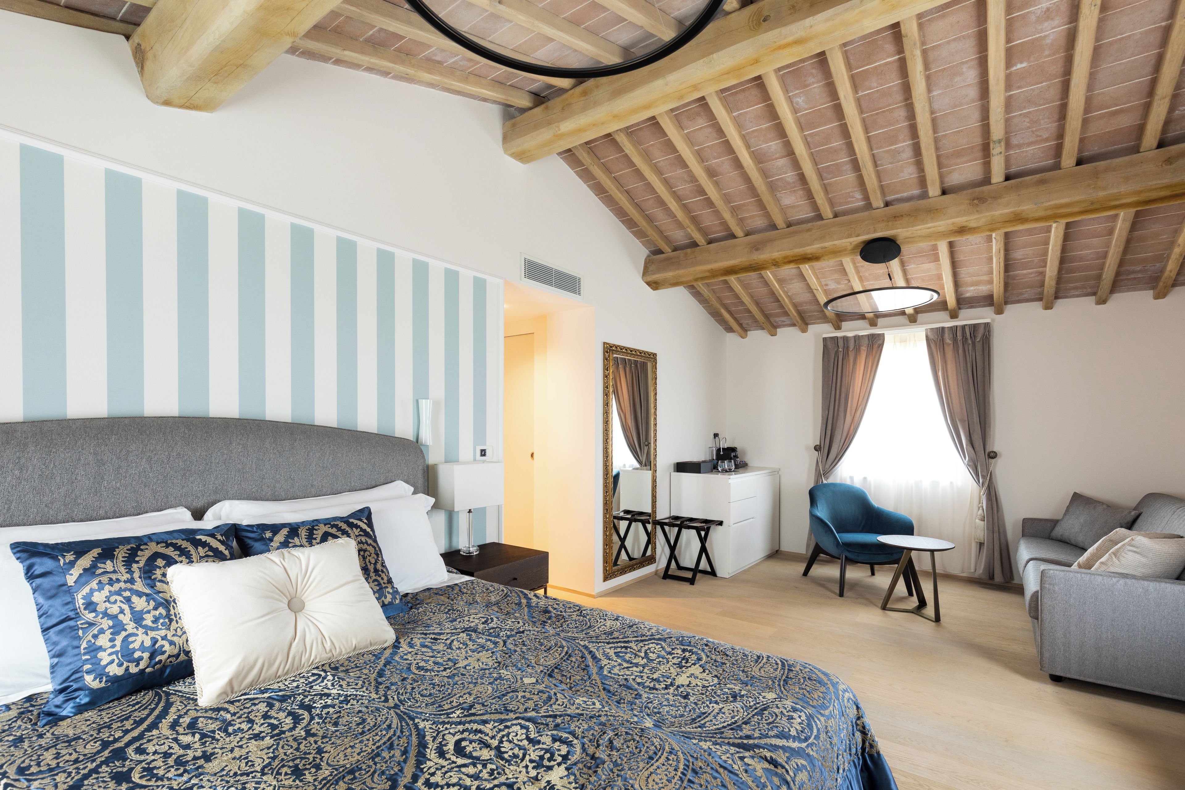A bedroom with a large bed, a desk, a chair, and a sofa.