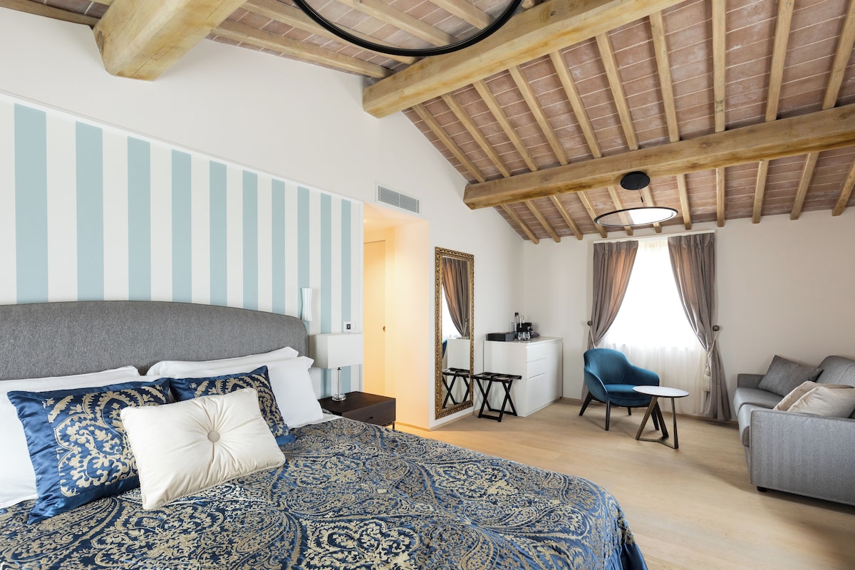 A bedroom with a large bed, a desk, a chair, and a sofa.